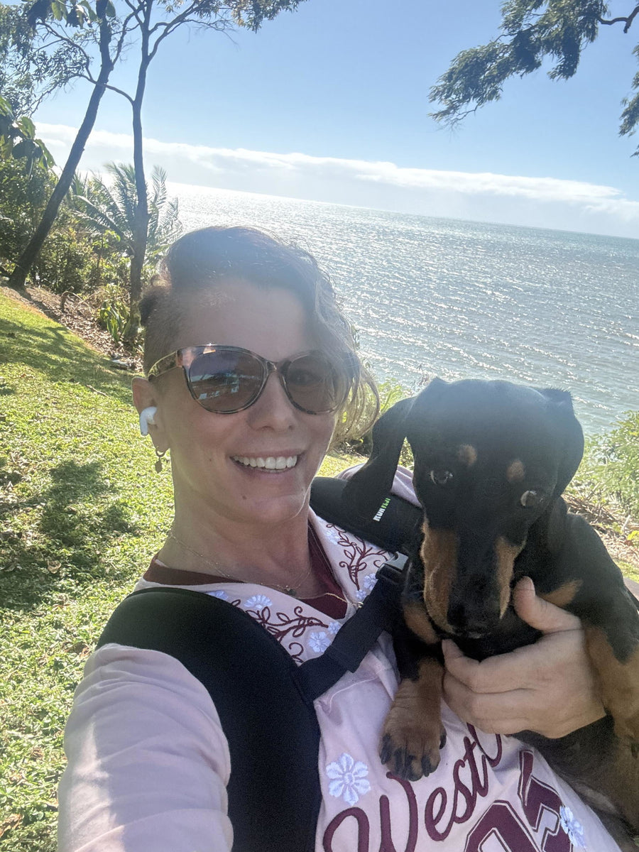 Cassie W. by the sea holding her small dog while wearing her RUKVEST