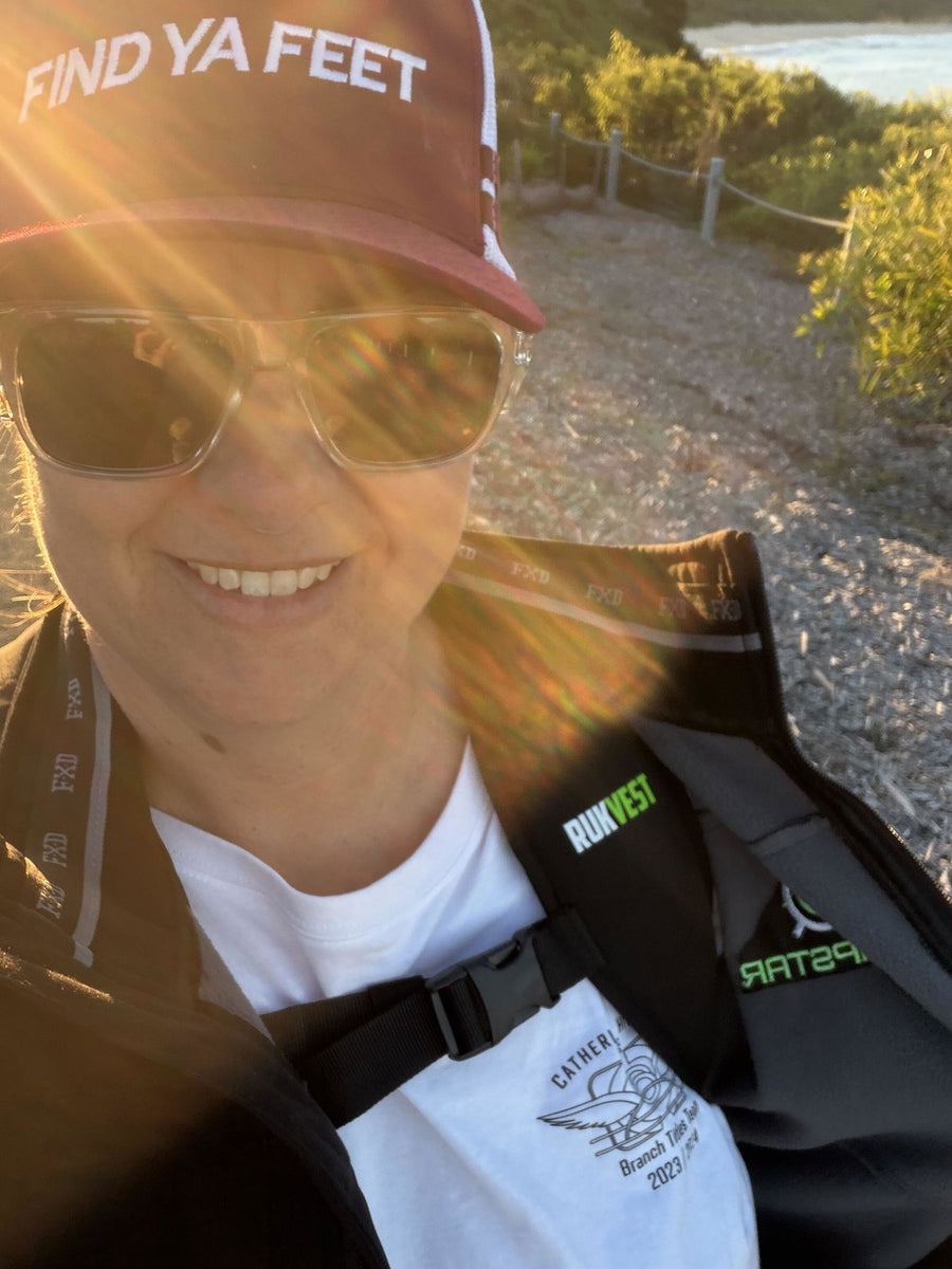 Smiling RUKVEST customer in a cap and sunglasses on a coastal walk