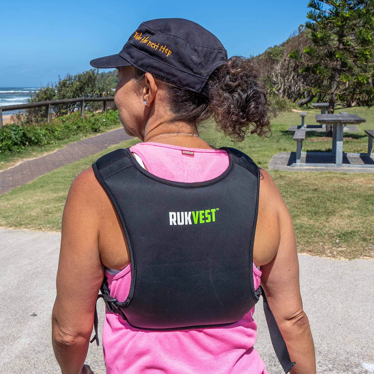 Person wearing a black Rukvest vest outdoors near a beach