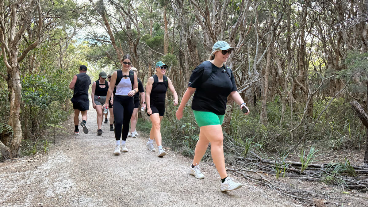 Group of people rucking on a trail through a forest wearing a RUKVEST weighted vest